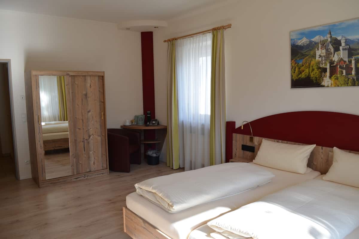 A bedroom with a large bed, a desk, a chair, and a mirror.