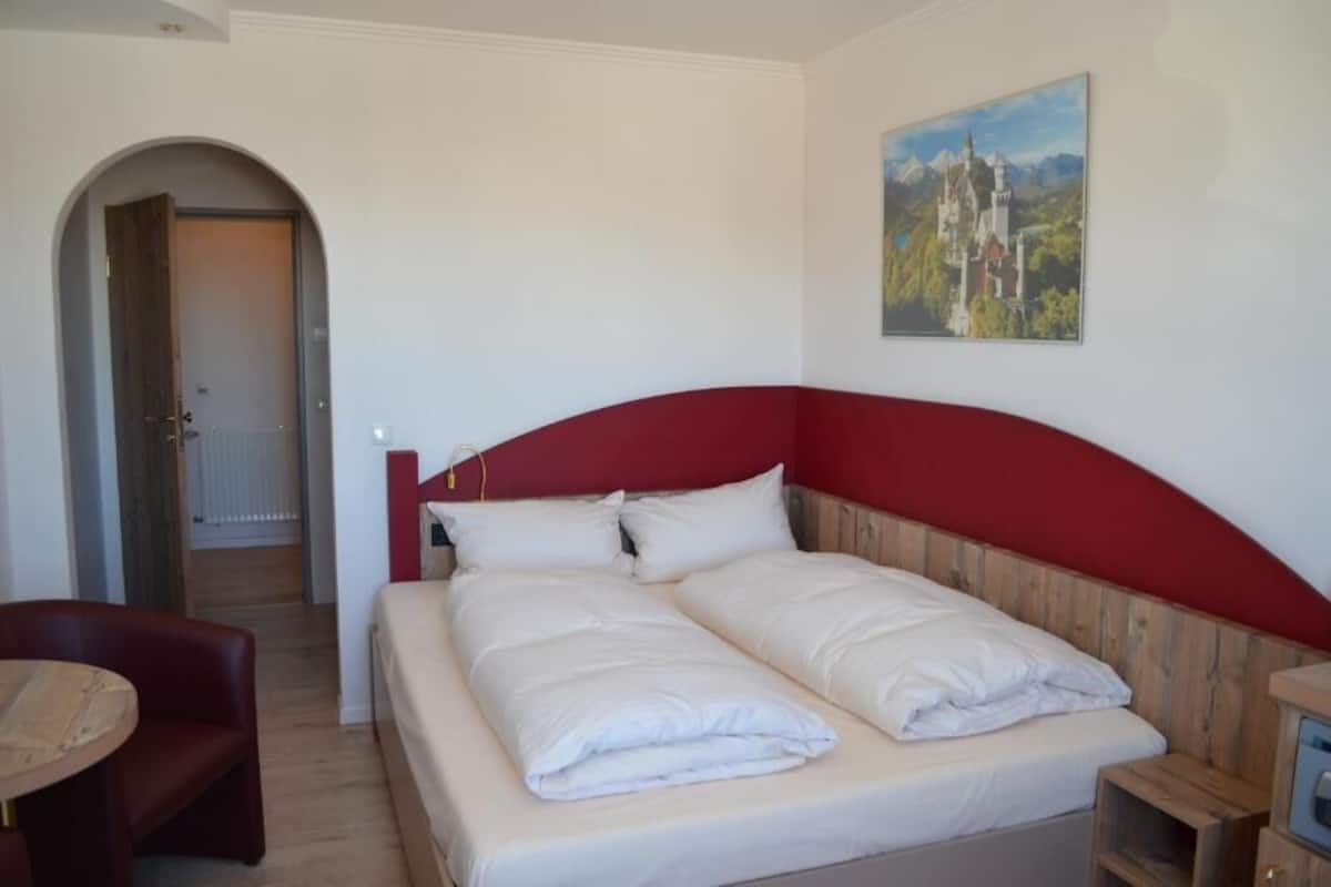 A bedroom with a bed, a chair, and a painting on the wall.