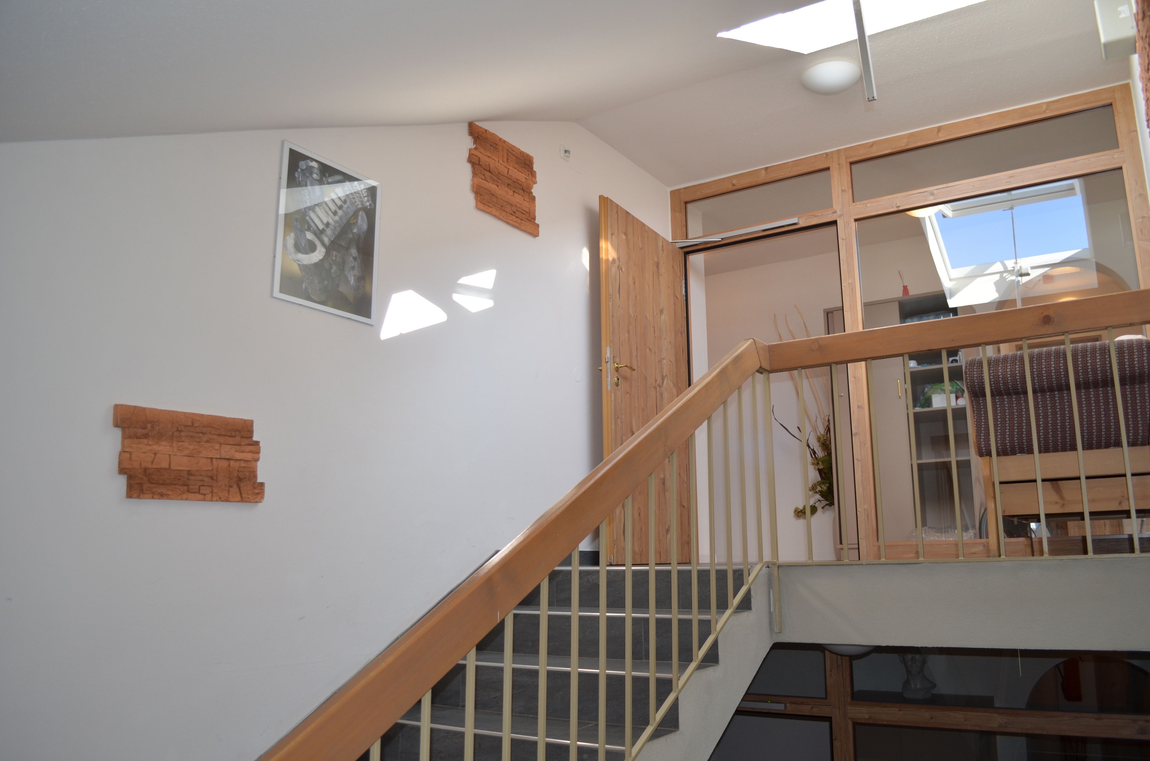 A staircase with wooden railings and a view of a room with a bed and a window.