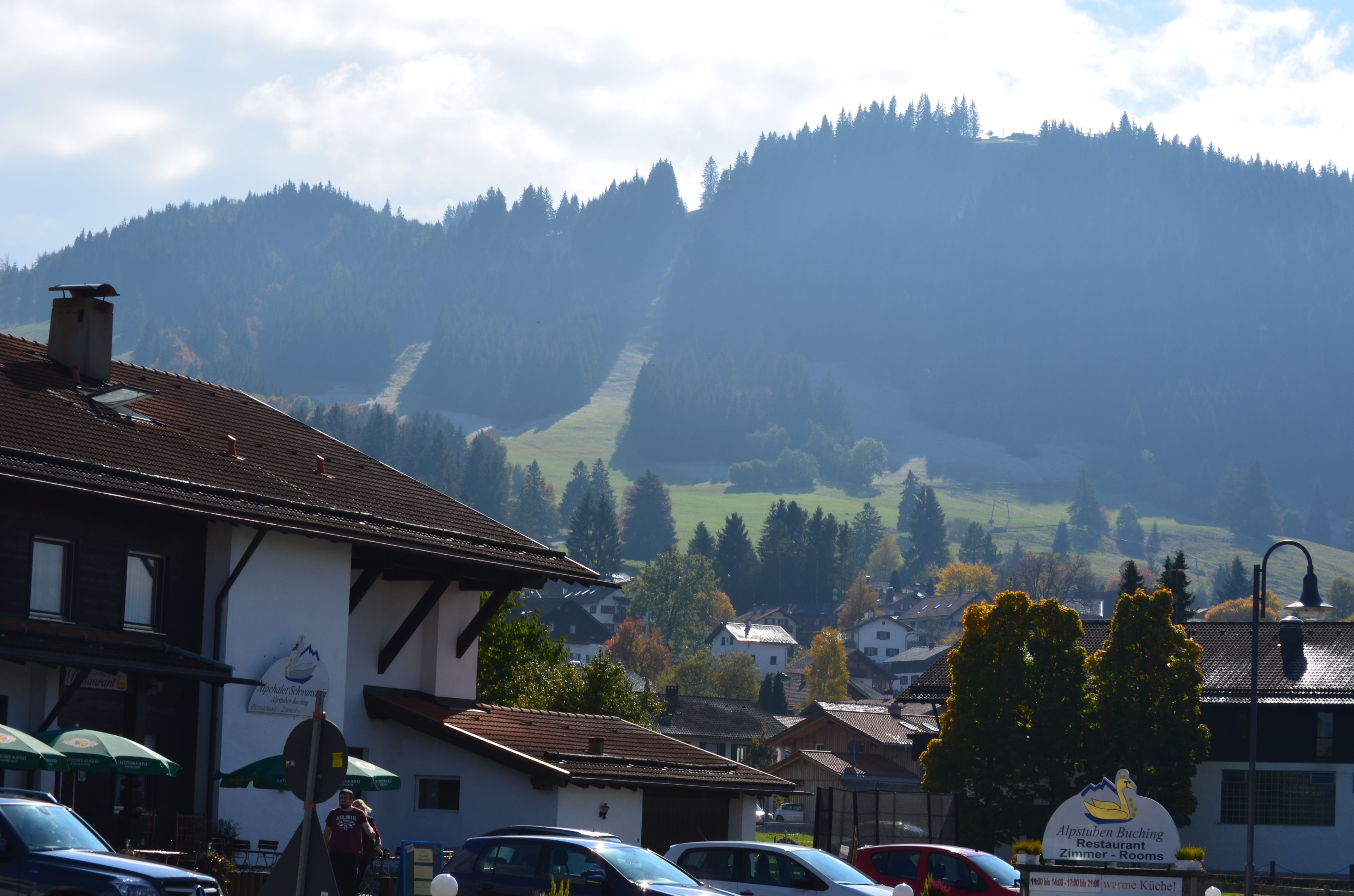 Un edificio con un letrero que dice 'Alpsten Buching Restaurant Zimmer - Rooms' y una vista de una montaña al fondo.