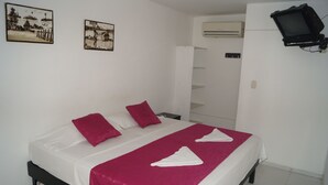A double bed with white and pink bedding, two pillows, and a red throw blanket.