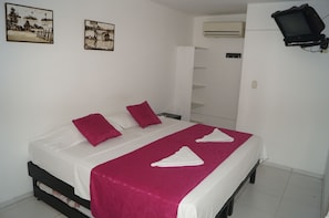A double bed with white and pink bedding, two pillows, and a red throw blanket.