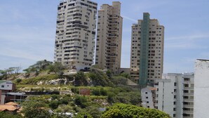 A multi-story hotel with balconies, located on a hillside with surrounding greenery.