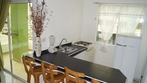 A kitchen with a black countertop, a sink, a stove, and three wooden chairs.
