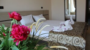Una habitación de hotel con cama, espejo y planta en maceta con flores.