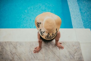 A person sitting on a tiled floor near a pool with a straw hat. - Vila Sangria (Navodari)