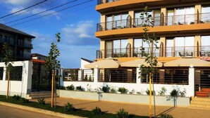Un hotel de varios pisos con balcones, una zona de estar al aire libre cubierta y una vista a la calle con señal de no estacionamiento.