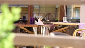 Un área de comedor al aire libre con muebles de mimbre y una mesa dispuesta con vasos y una jofaina.