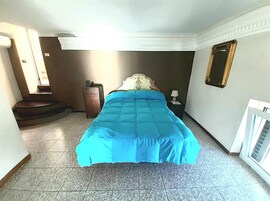Ein Hotelzimmer mit einem Bett, einem Nachttisch, einem kleinen Schrank, einem Spiegel und einer Heizung.