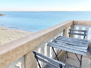 A balcony with a view of the sea, featuring a concrete railing and a wooden table and bench. - Castello Miramare (Genoa)