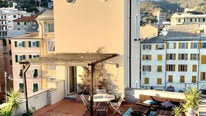 Terraço no terraço com pérgola, mobiliário de exterior e plantas em vasos.