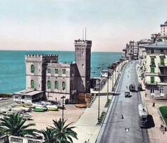 Ένα αστικό τοπίο σε παράκτια περιοχή, με ένα επιβλητικό ψηλό κτίριο, μια γραμμή τραμ και μια μαρίνα με σκάφη.