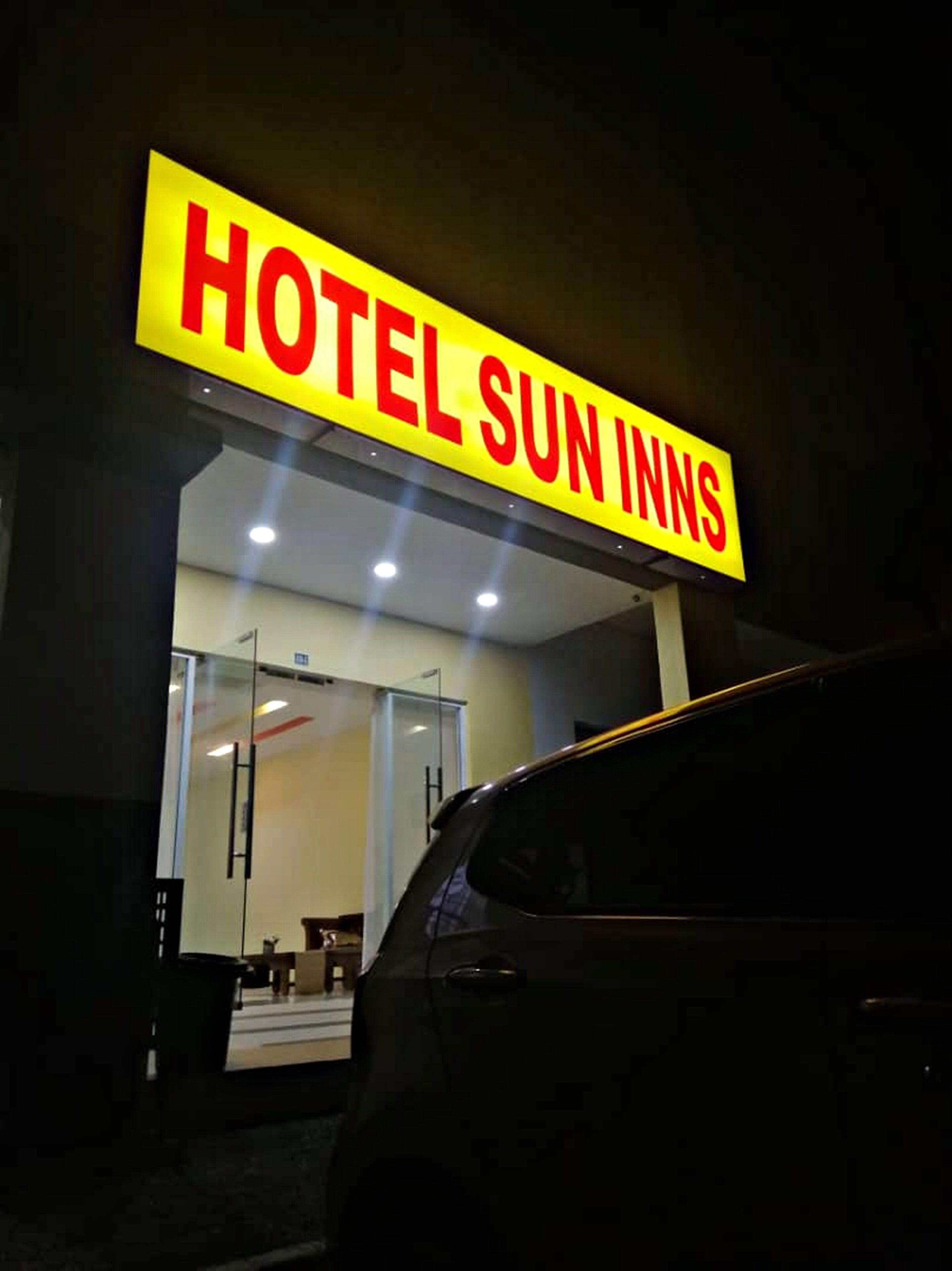 A hotel sign reading "HOTEL SUN INNS" at night.