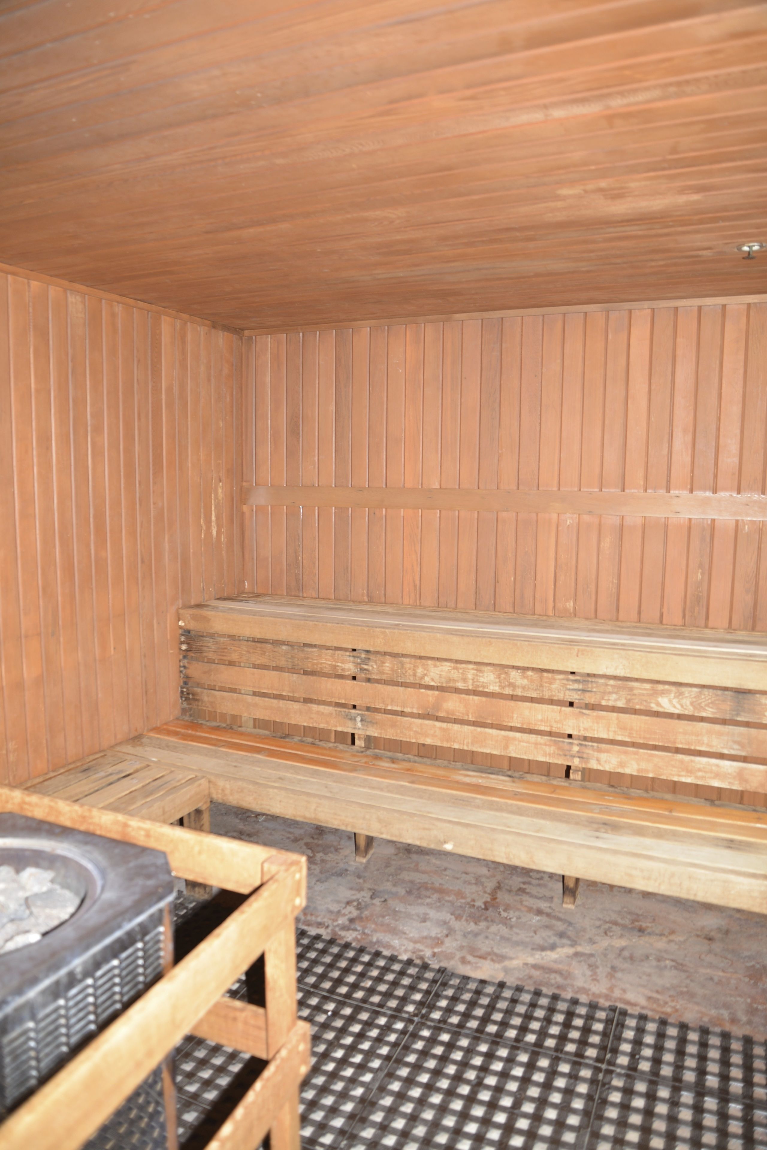 A sauna with wooden benches and a metal grate floor.