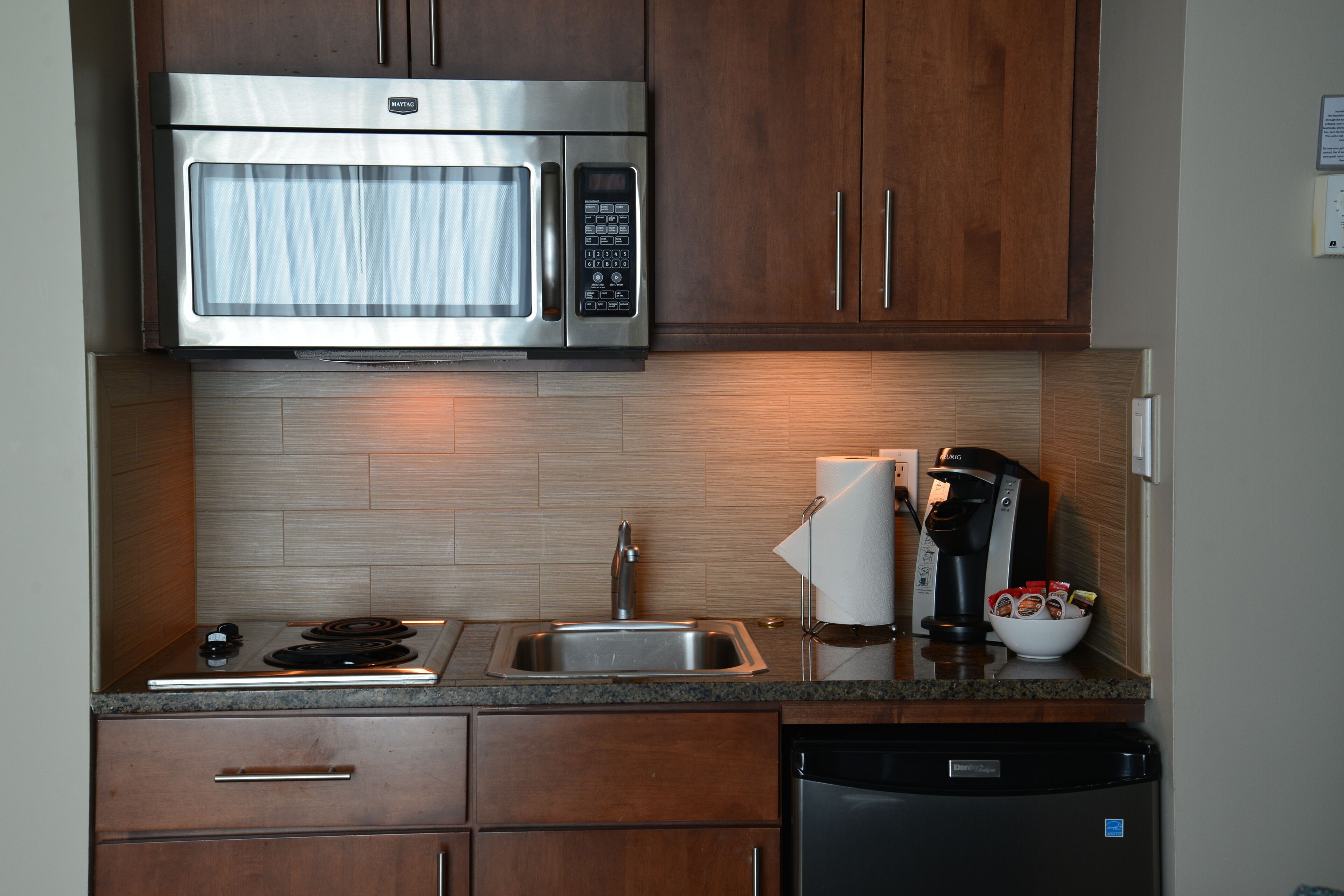 A modern kitchen with a stainless steel microwave, a coffee maker, and a dishwasher.