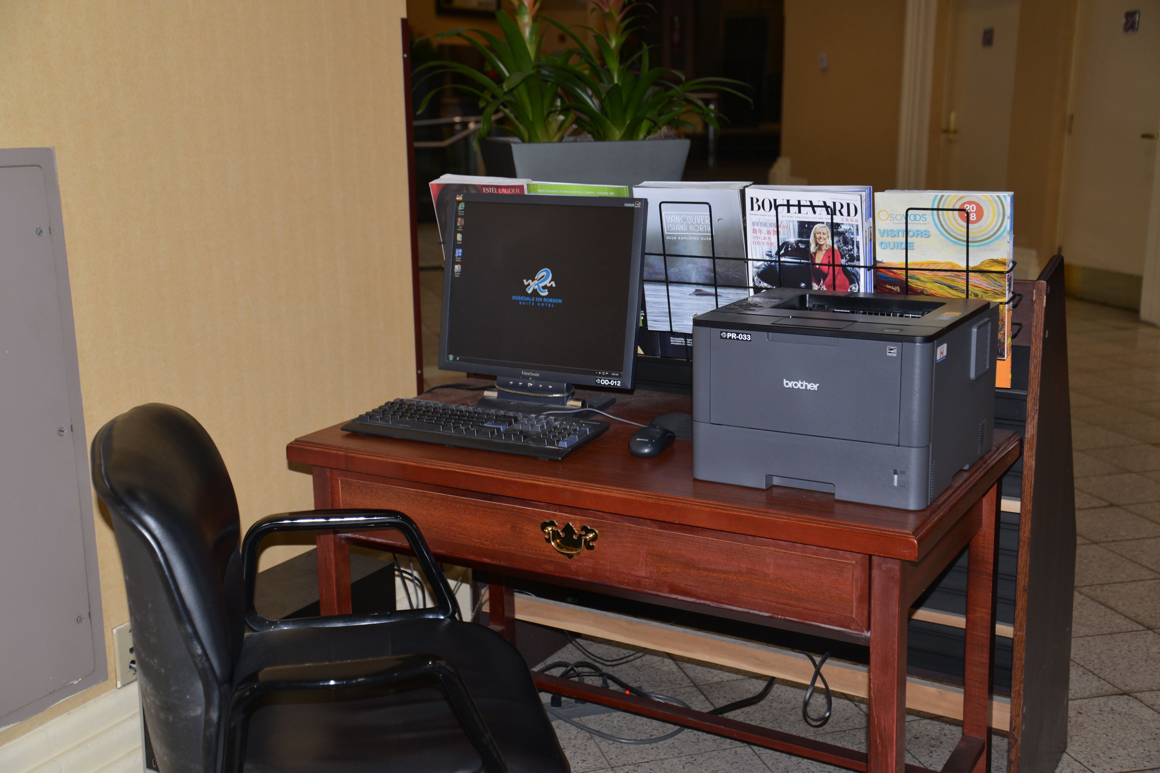 A wooden desk with a desktop computer, a printer, and a keyboard.