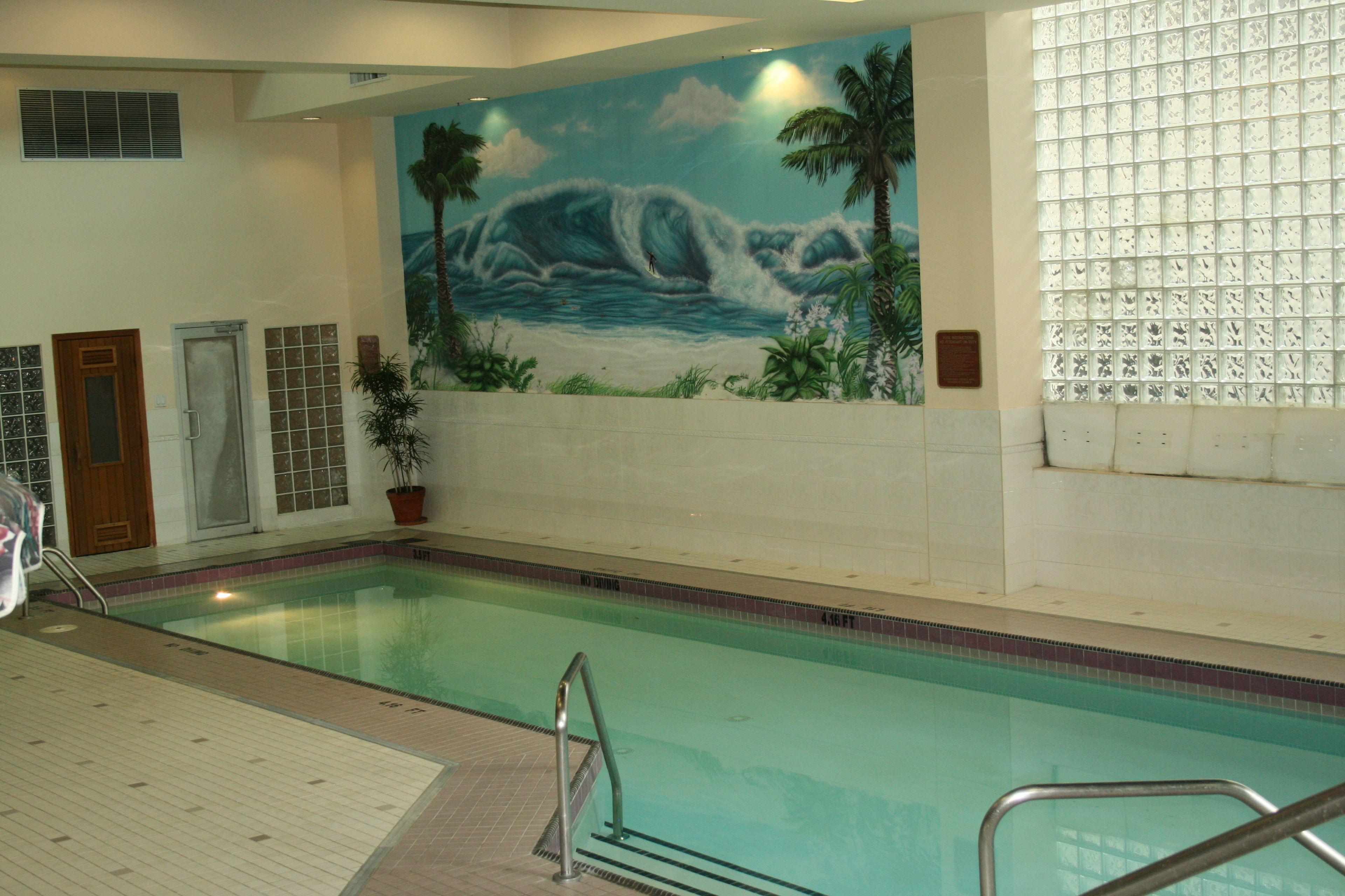 Ein Hallenbad mit Wandgemälde von einer Welle und Palmen.