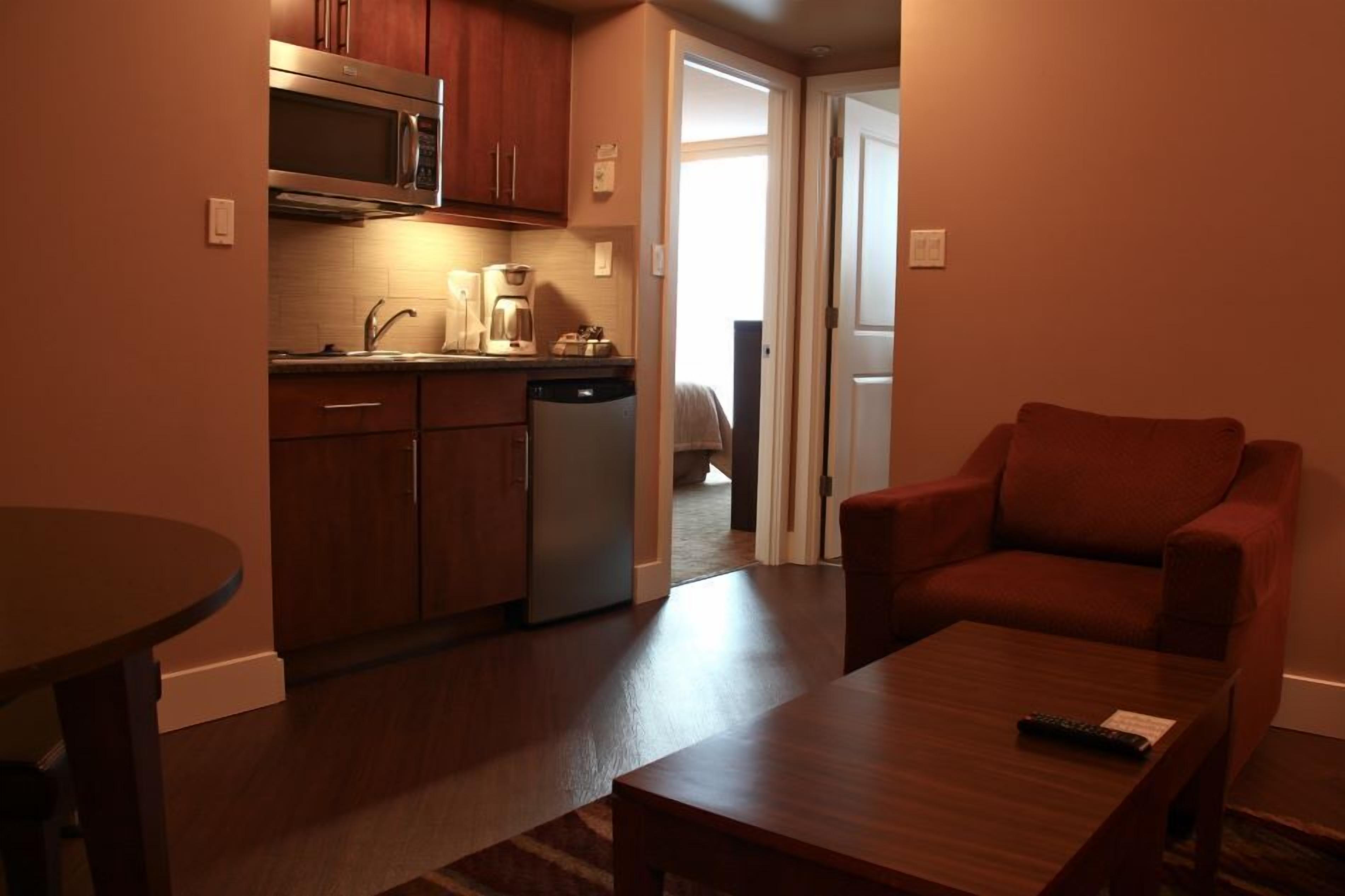 Un espacio habitable compacto con kitchenette, comedor y zona de estar.