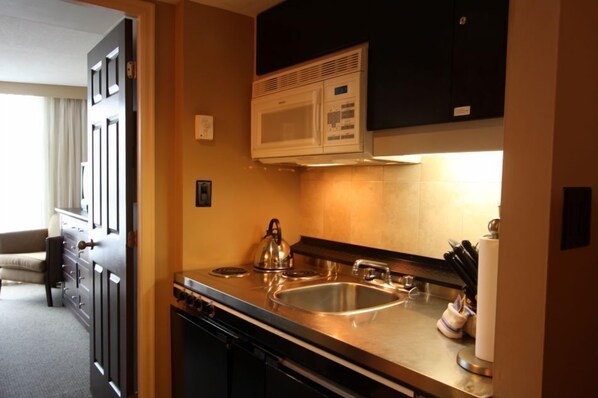 A compact kitchen with a microwave, stove, and sink.