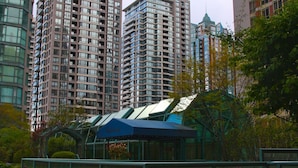 A high-rise building with multiple balconies, a glass facade, and a brick-paved walkway with potted plants. - Rosedale Condominiums (Vancouver)