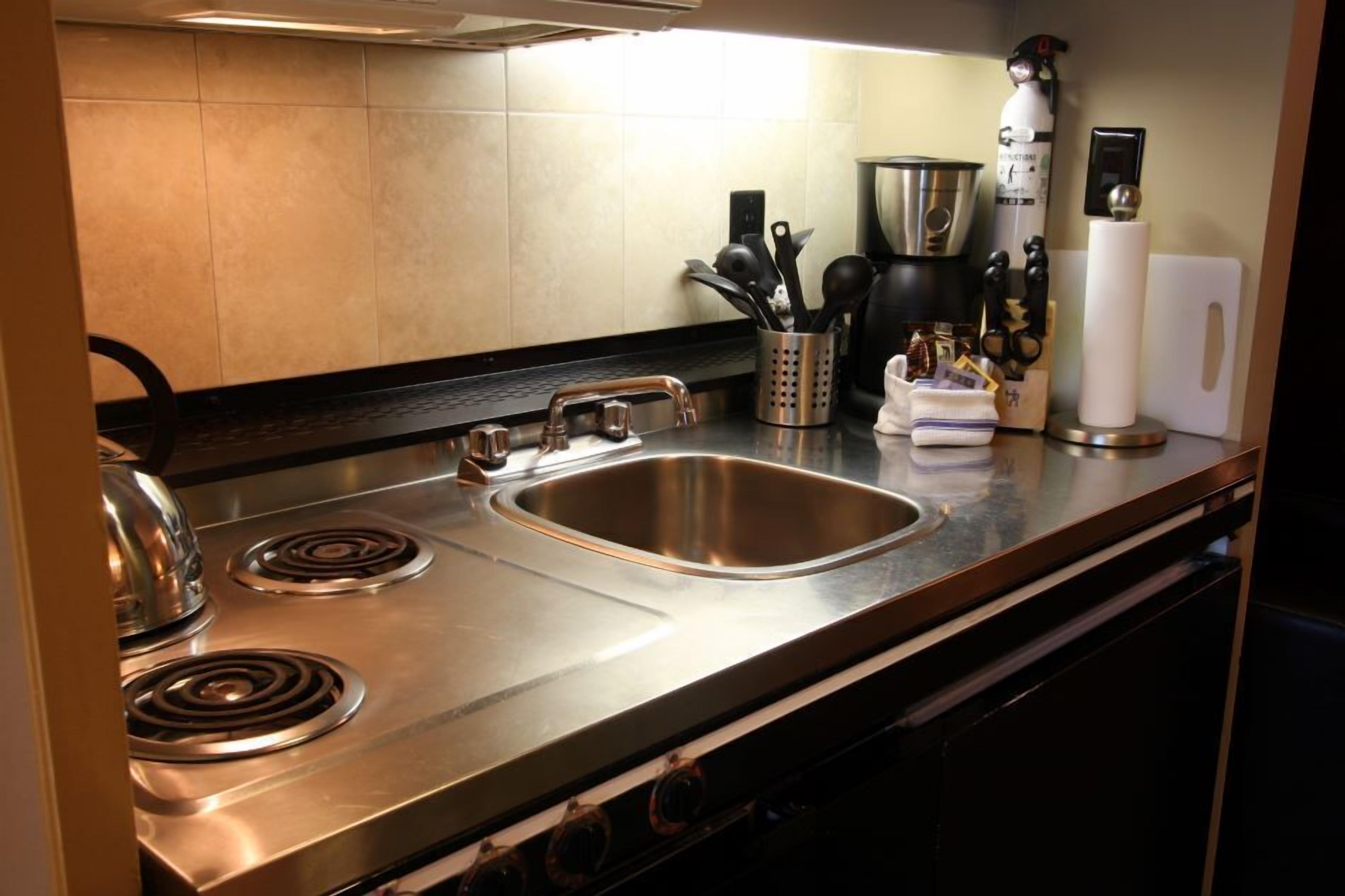 Una cocina moderna con electrodomésticos de acero inoxidable, un lavamanos y una cafetera.