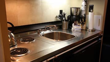 Una cocina moderna con electrodomésticos de acero inoxidable, un lavamanos y una cafetera.
