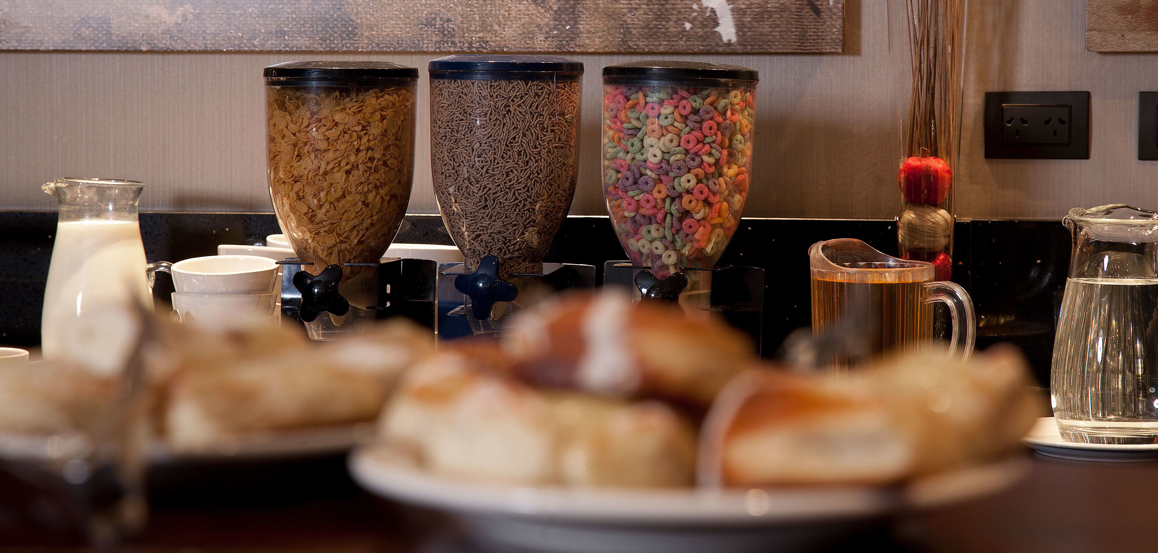 Un buffet per la colazione con cereali, latte e una brocca d'acqua.