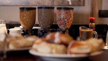 Un buffet per la colazione con cereali, latte e una brocca d'acqua.