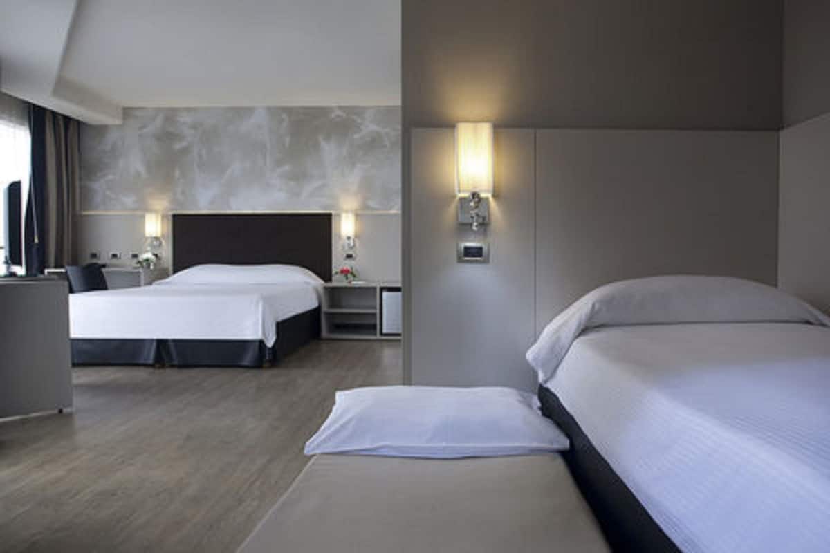 A hotel room with two beds, a desk, and a nightstand.