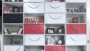 A room with a white bookshelf containing various items, two red chairs, and a small round table. - Two Hotel Buenos Aires (Buenos Aires)
