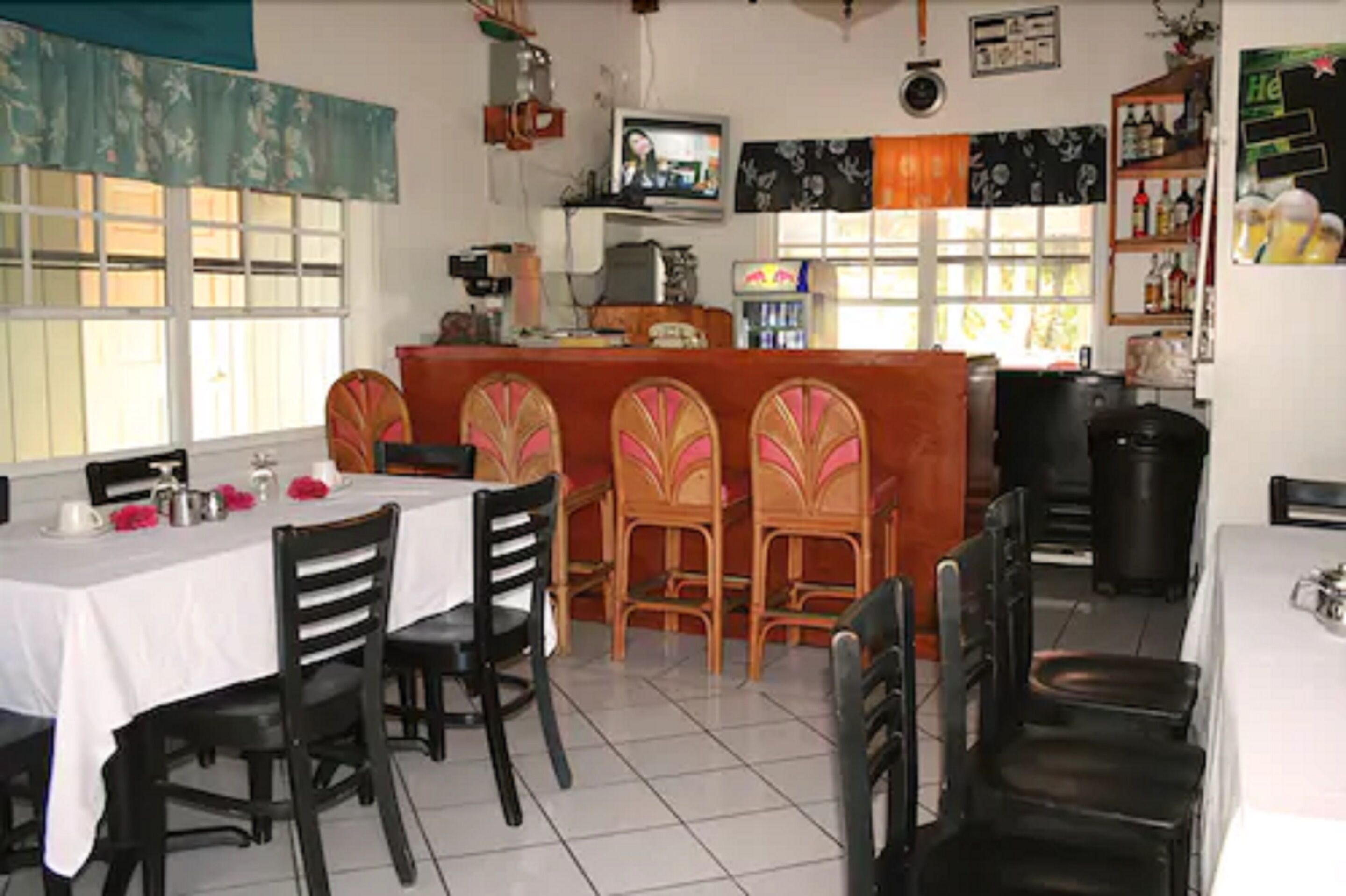 A dining area with a bar, wooden chairs, and a television.