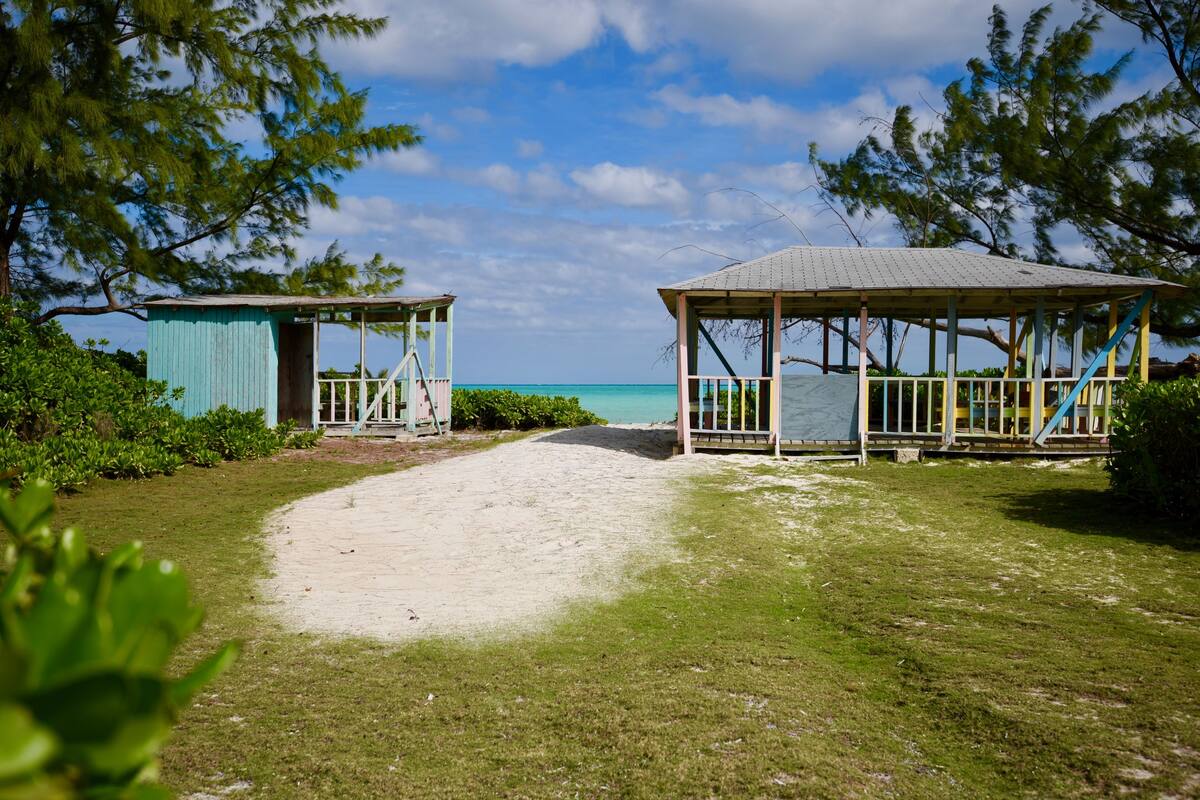 A beachside pathway leading to two beach huts with a clear view of the ocean.