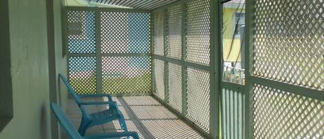 A covered waiting area with blue chairs and a patterned fence.