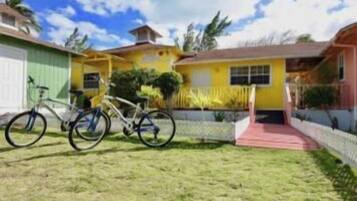 A residential property with a front yard, a bicycle, and a red pathway leading to the entrance.