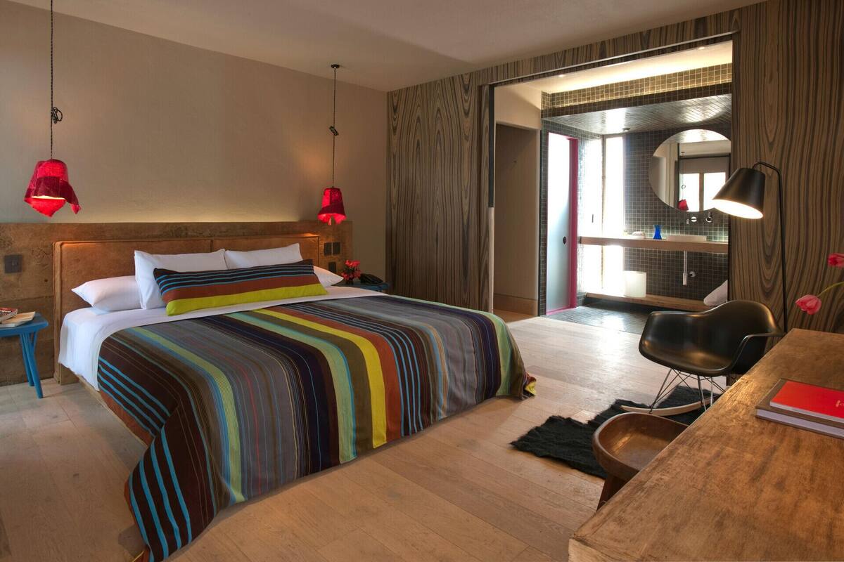 Une chambre d’hôtel comprenant un lit, une table de chevet et un bureau avec une chaise.