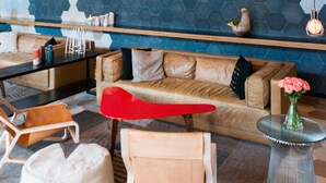 Een modern interieur met houten balken in het plafond, een geometrisch wandontwerp en eigentijdse meubels.