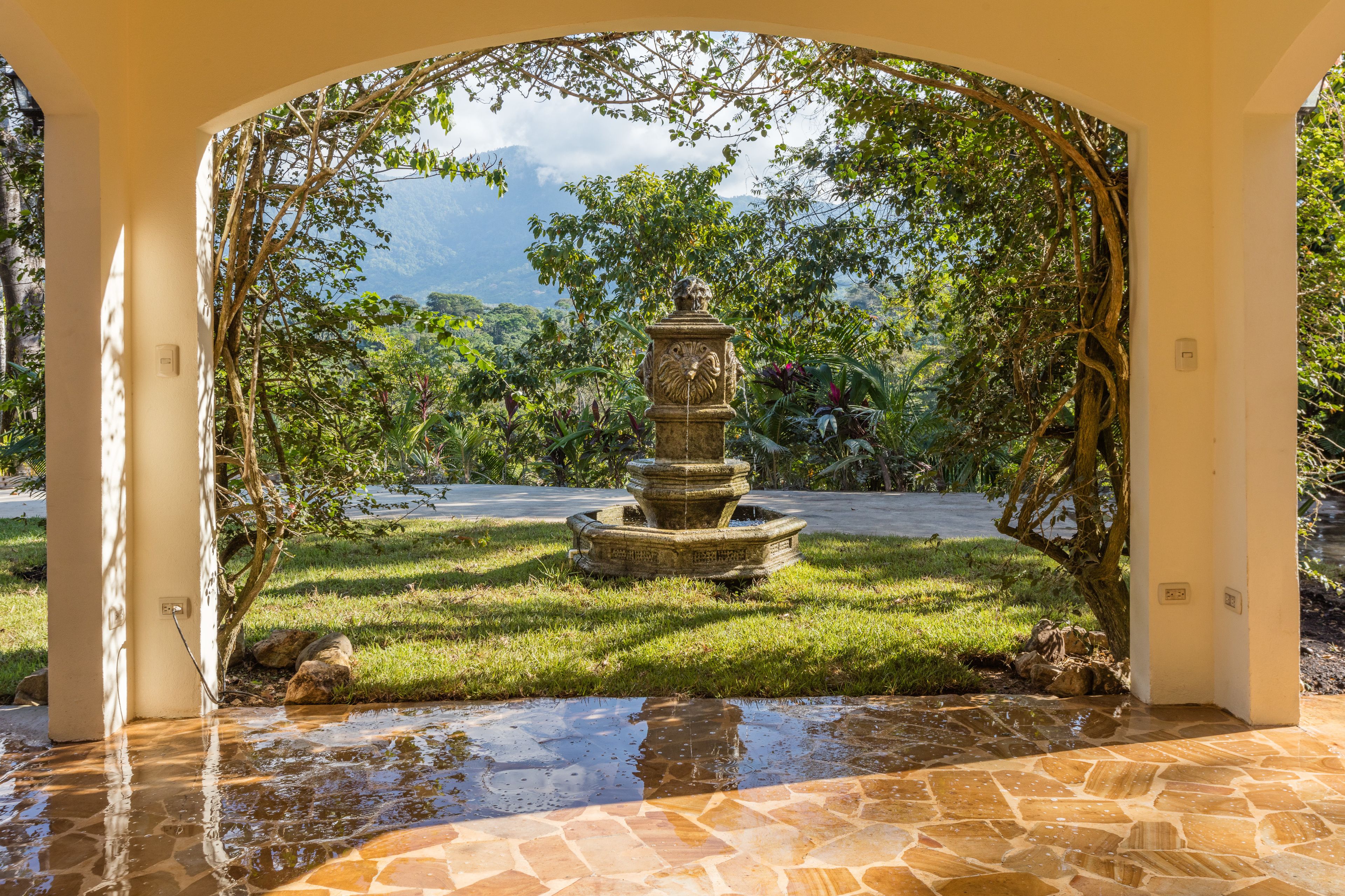 Uma fonte de pedra em um jardim, com vista para montanhas.