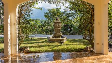 Uma fonte de pedra em um jardim, com vista para montanhas.