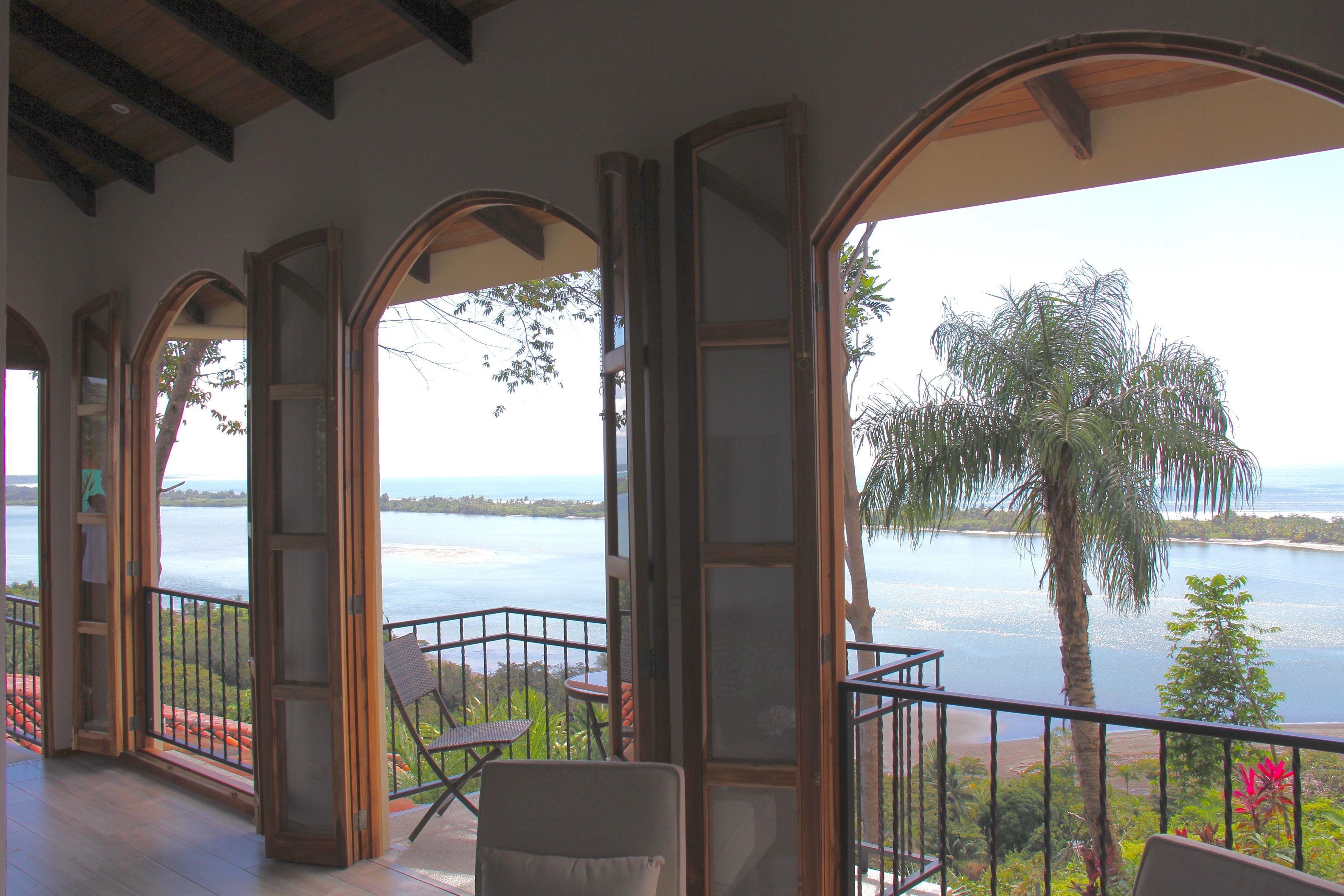 A balcony with a view of a body of water and palm trees.