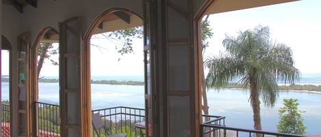 A balcony with a view of a body of water and palm trees.