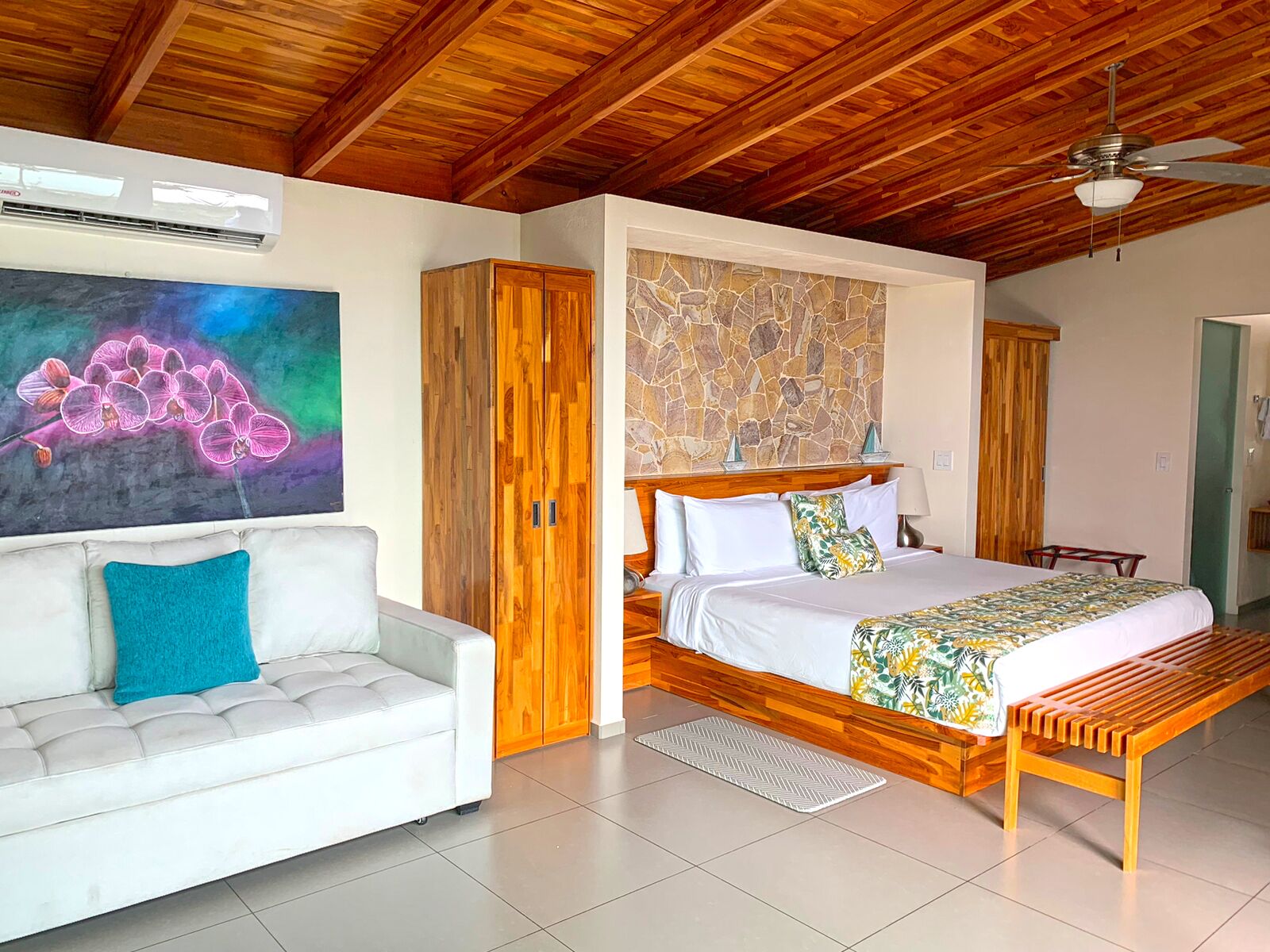 Ein Schlafzimmer mit Bett, Holz-Kopfteil und Steinwand.
