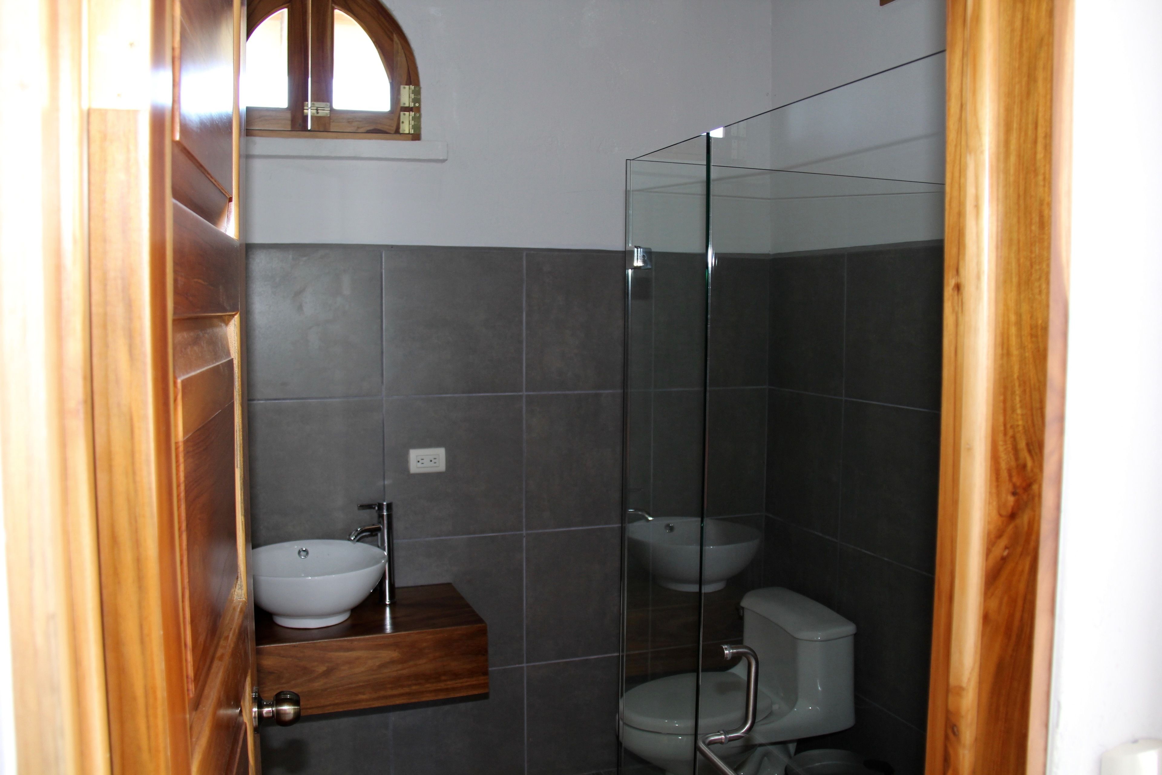 A bathroom with a wooden vanity, a white sink, and a glass shower enclosure.