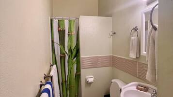 Un baño con inodoro, lavamanos y cortina de ducha.