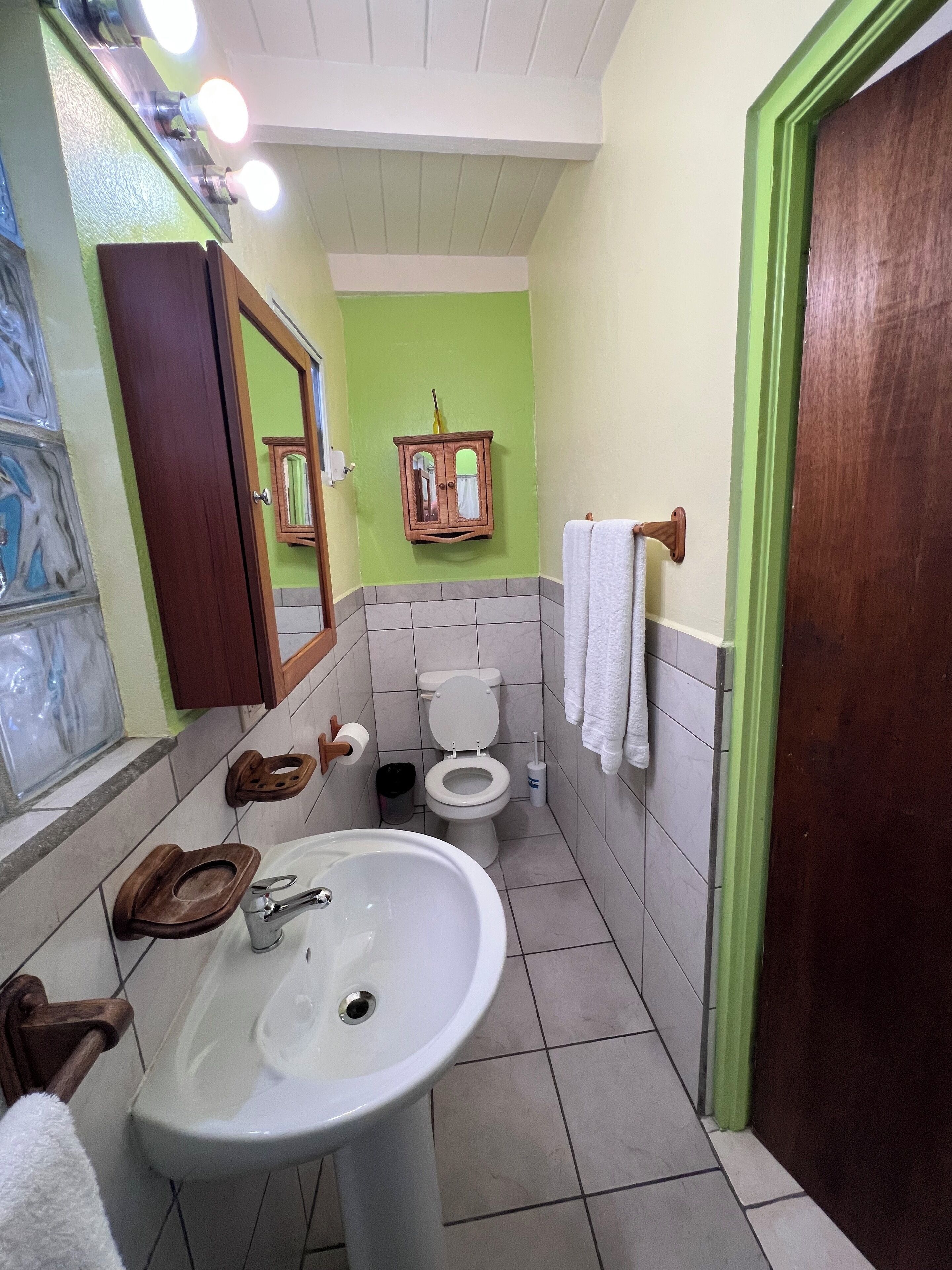 A bathroom with a sink, toilet, and mirror.
