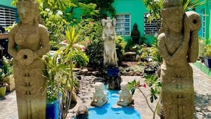 Une cour agrémentée de statues, d’un petit bassin et d’une végétation luxuriante.
