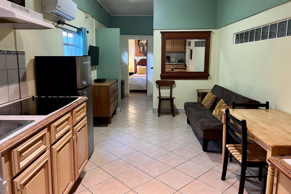 A compact living space with a kitchenette, a dining area, and a bedroom.