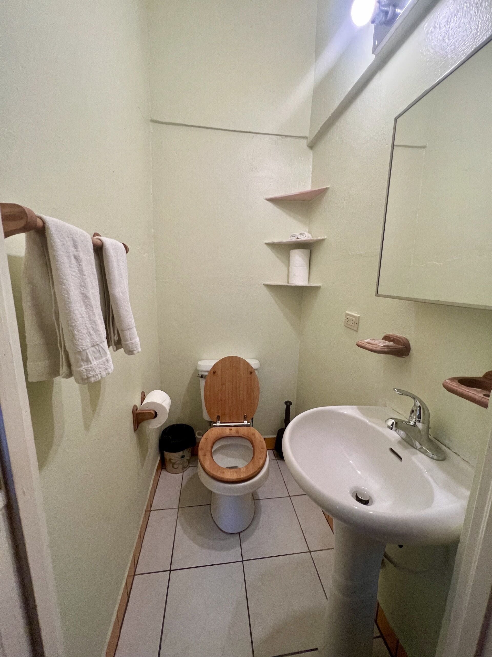 Un baño pequeño con inodoro, lavamanos y estanterías.