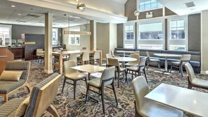 A modern hotel lobby with seating areas, a reception desk, and large windows offering views. - Residence Inn Woodbridge Edison/Raritan Center (Woodbridge)