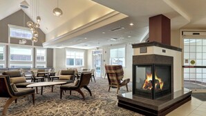A spacious lobby with a fireplace, comfortable seating, and large windows. - Residence Inn Woodbridge Edison/Raritan Center (Woodbridge)