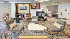 A lobby with seating areas, a fireplace, a television, and a reception desk. - Residence Inn Woodbridge Edison/Raritan Center (Woodbridge)